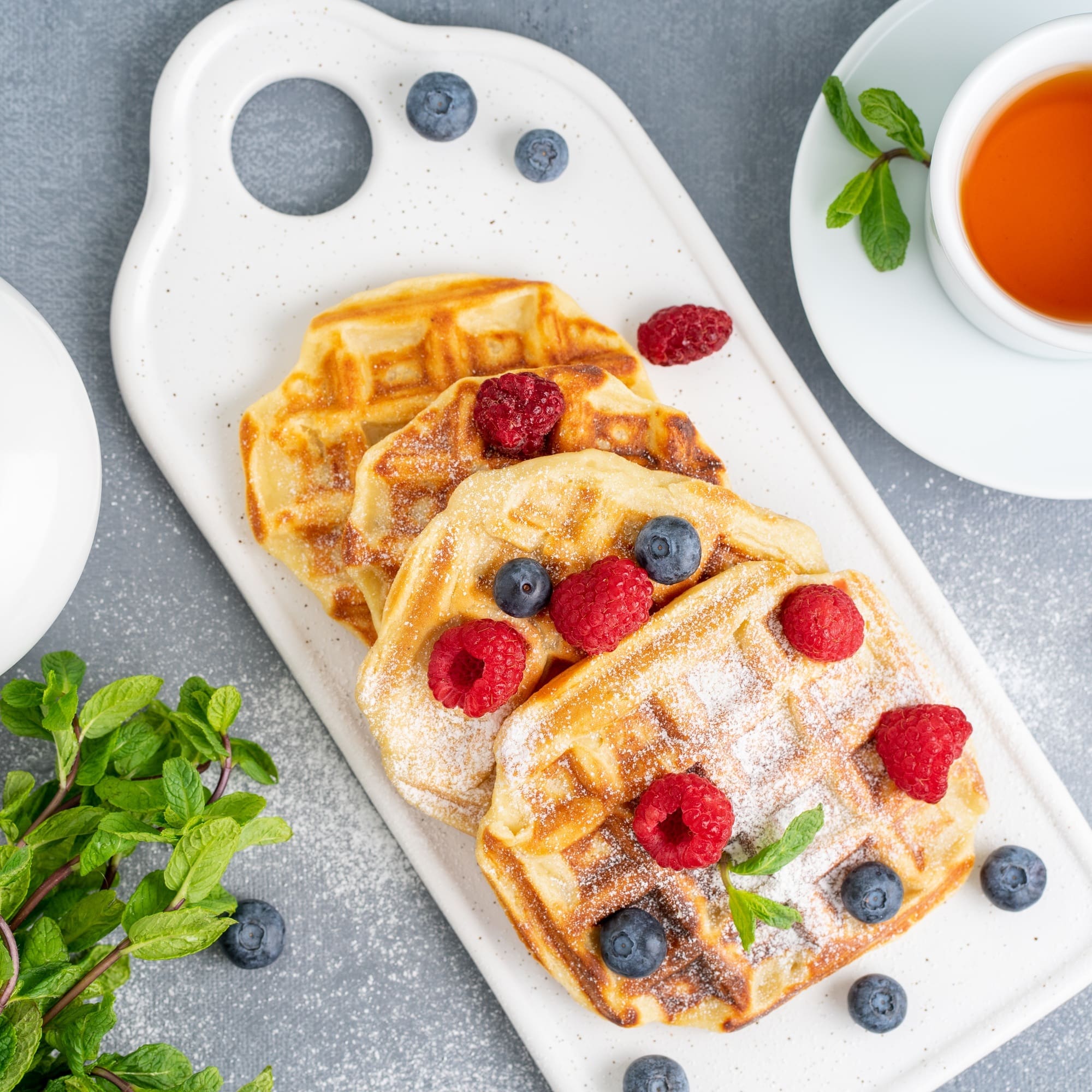 Belgian waffles with raspberries, blueberries, tea, top view. Healthy homemade breakfast