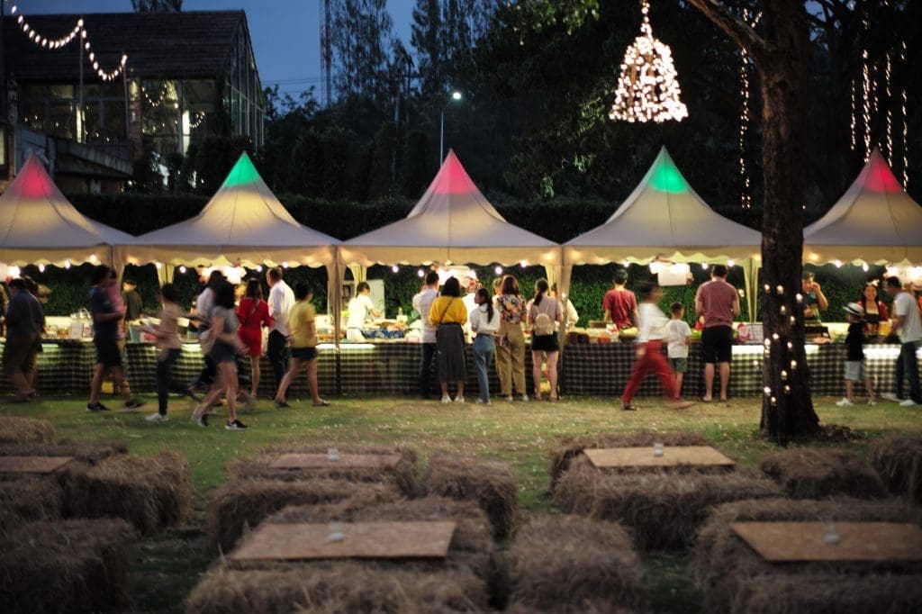 The Best Food Festivals in Quebec in 2025 Blurred motion people walk in the food festival at night with decorative bokeh light in background