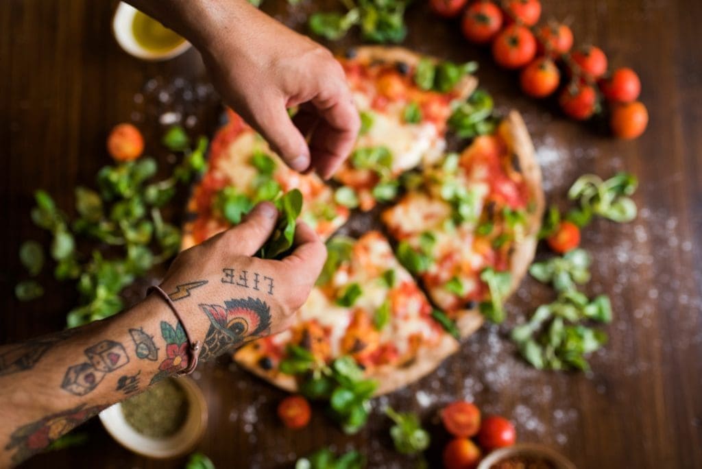 Passion et saveurs : Les meilleures pizzerias Québec (2025) Chef garnishing pizza with basil leaves on kitchen worktop