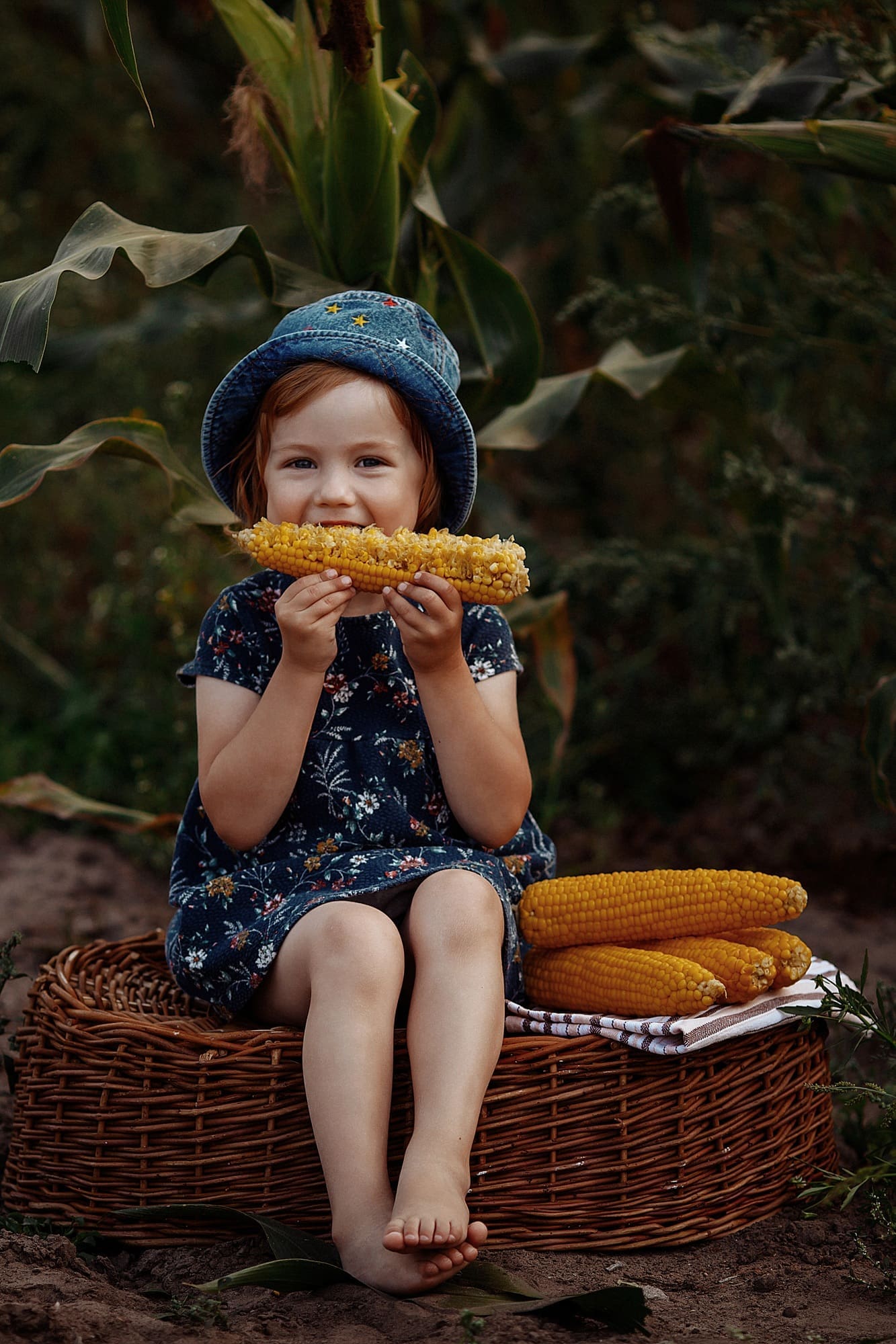 Happy little girl holding an ear of corn.